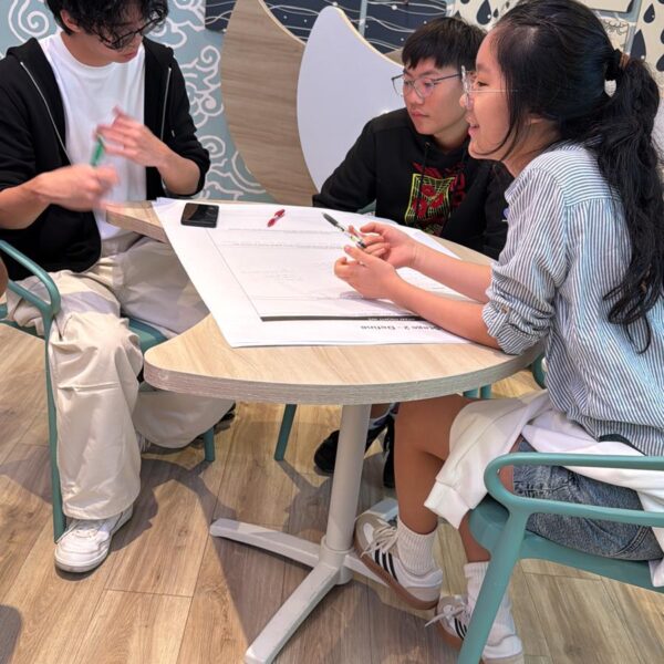 Three young people sitting at a table, collaborating on a project in Youth Leadership Camp