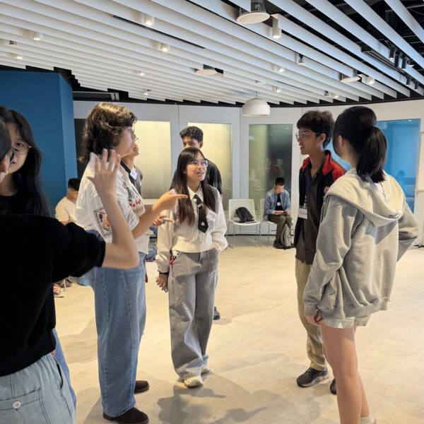 A group of students talking and gesturing in a modern indoor space at Youth leadership and Communication camp