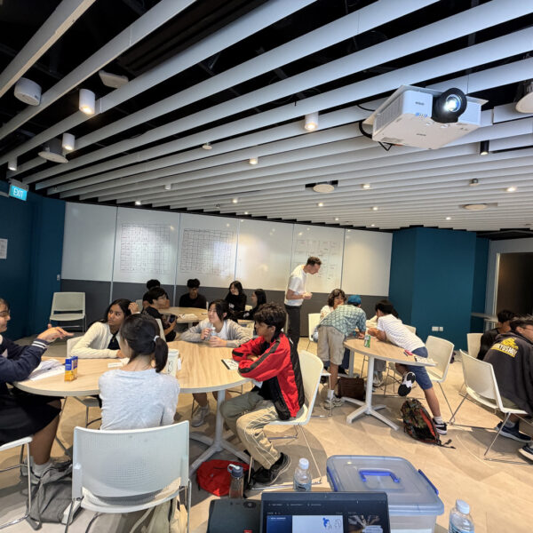 Students sitting at round tables in a modern classroom, engaged in group discussions and activities