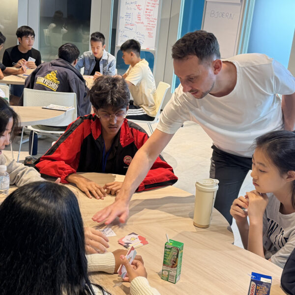 A facilitator helps students with a card-based group activity in a classroom