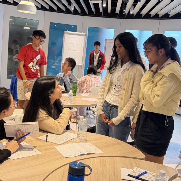 Diverse group of young people collaborating and discussing during a workshop in a modern classroom