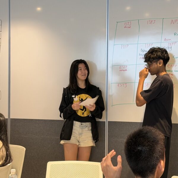 Two people stand in front of a whiteboard grid of Myers-Briggs personality types during a group activity