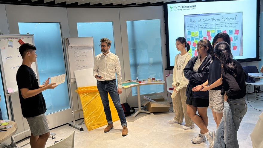 A student presents his work to a facilitator and peers during a Youth Leadership workshop
