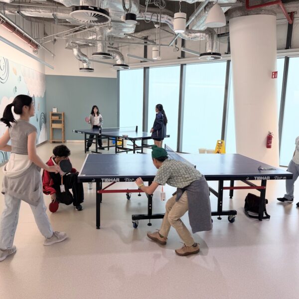 Several people playing table tennis in a bright, modern indoor recreational space