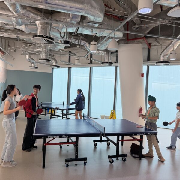 Young people playing table tennis in a modern indoor recreational space with large windows