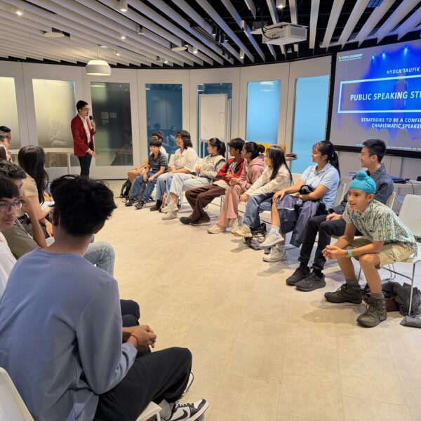 A speaker presents Public Speaking Strategies to a group of students seated in a circle