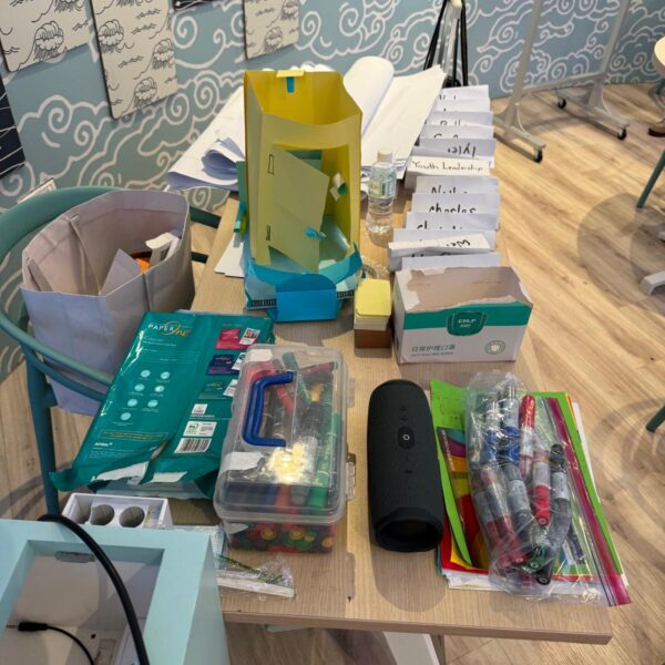 A table cluttered with workshop supplies for Youth Leadership and Communication camp